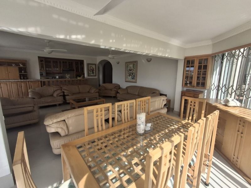Spacious open-plan living and dining area featuring built-in cabinetry, ceiling fans, and classic coved cornicing, offering a functional layout for family living.