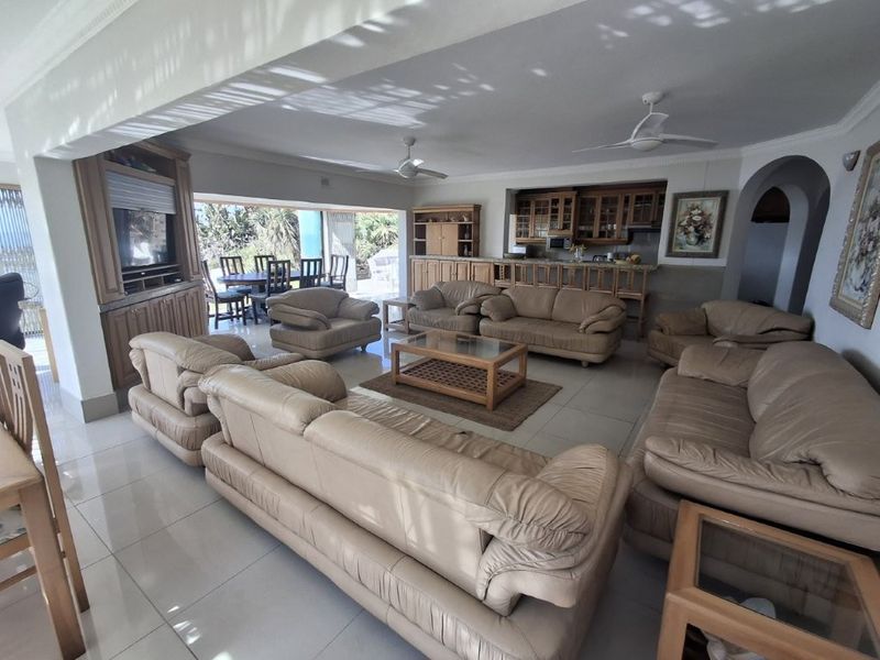 Spacious open-plan living and kitchen area featuring tiled floors, built-in cabinetry, ceiling fans, and large sliding doors leading to an outdoor patio.