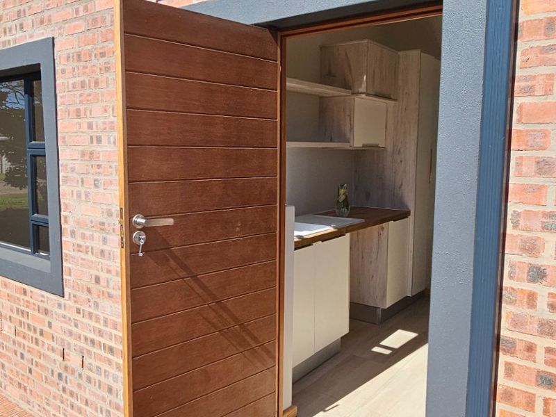 Exterior view of a modern brick home featuring a timber entrance door leading into a functional scullery area with built-in cabinetry and sink.
