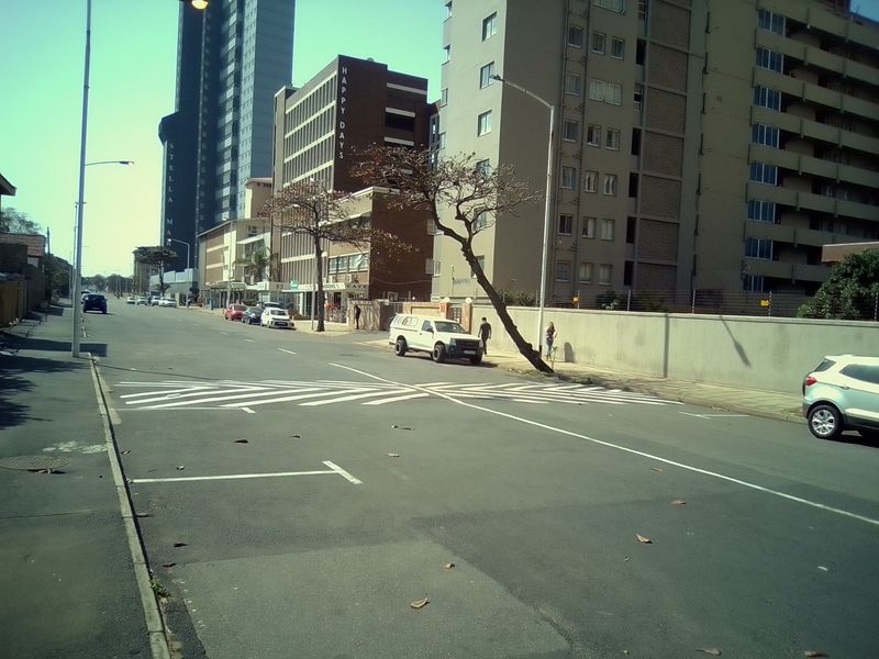 A street-level view showing the road, pavement, and surrounding apartment buildings in an urban residential area.