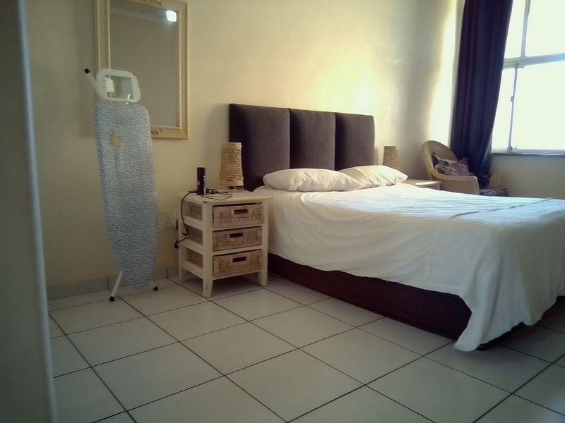 A bedroom featuring tiled flooring and a large window, providing natural light to the space.