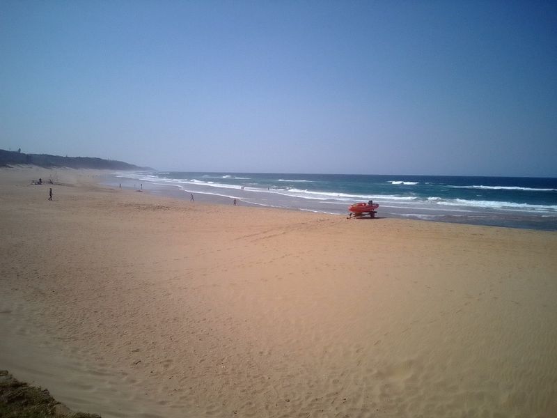 A scenic view of the sandy beach and ocean coastline, highlighting the natural surroundings of the property location.