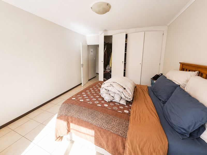 A bedroom featuring tiled flooring and built-in cupboards, providing functional storage space within the apartment.