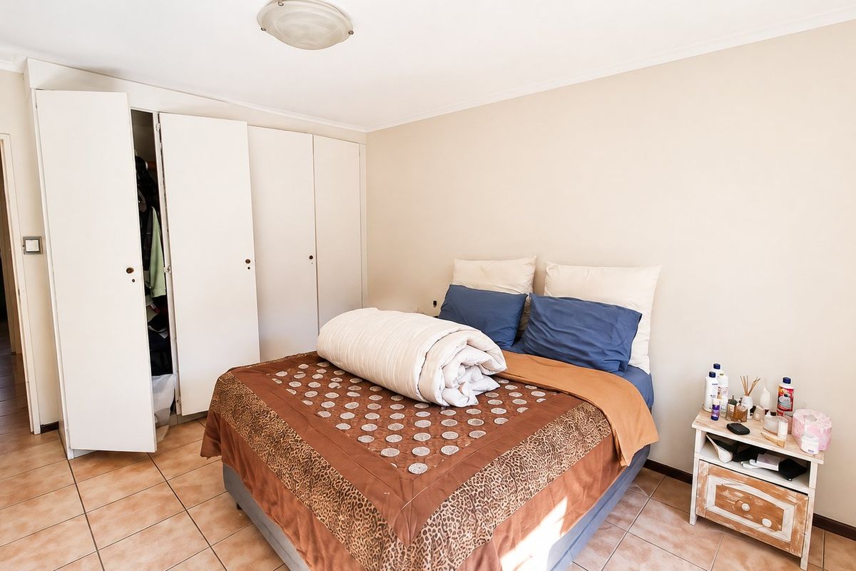 A bedroom featuring tiled flooring and built-in cupboards, providing functional storage space within the apartment.