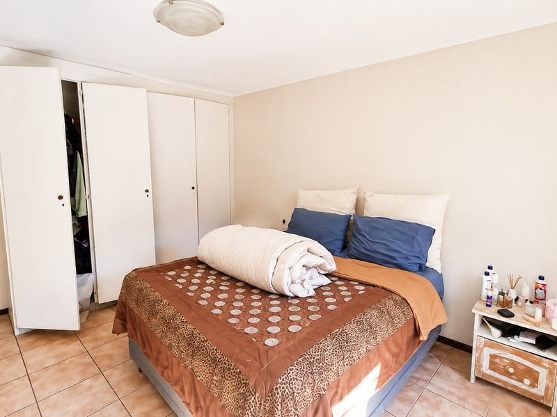 A bedroom featuring tiled flooring and built-in cupboards, providing functional storage space within the apartment.