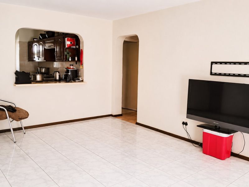 Open plan living area featuring tiled flooring, an arched doorway, and a convenient pass-through window connecting to the kitchen.