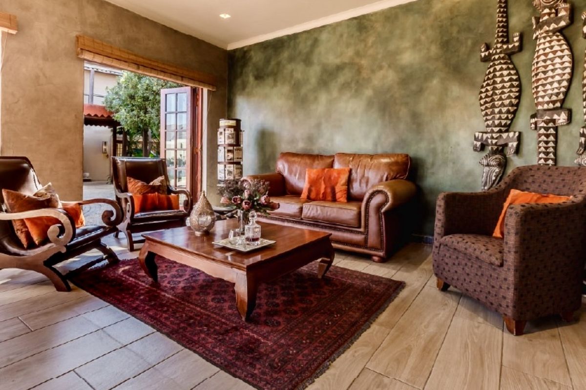 A well-maintained living room featuring tiled flooring, recessed lighting, and double wooden doors leading to an outdoor area.