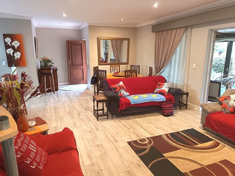 Spacious open-plan living and dining area featuring modern timber-look laminate flooring, recessed downlighting, and direct access to an outdoor patio through sliding glass doors.