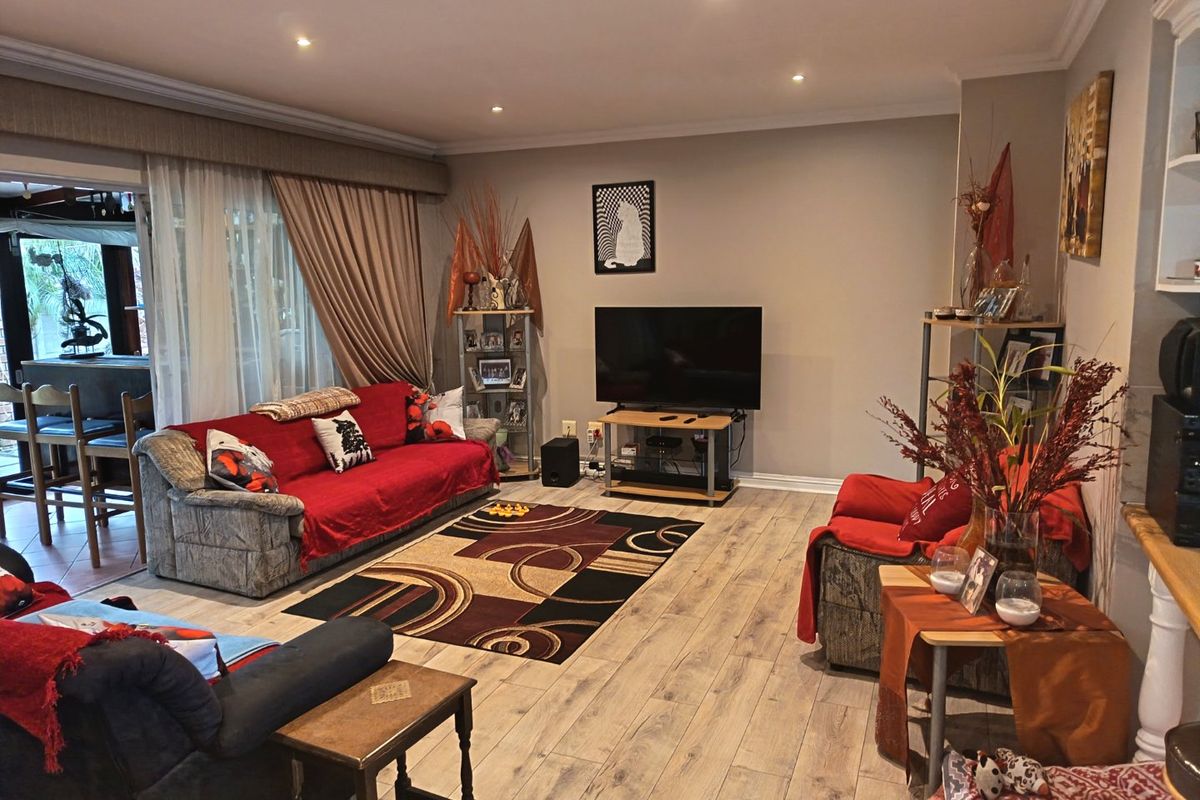 Spacious living room featuring laminate flooring, recessed downlighting, and a large sliding glass door providing access to the outdoor patio area.