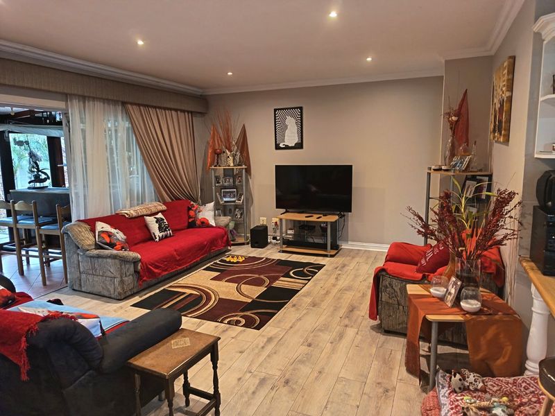 Spacious living room featuring laminate flooring, recessed downlighting, and a large sliding glass door providing access to the outdoor patio area.