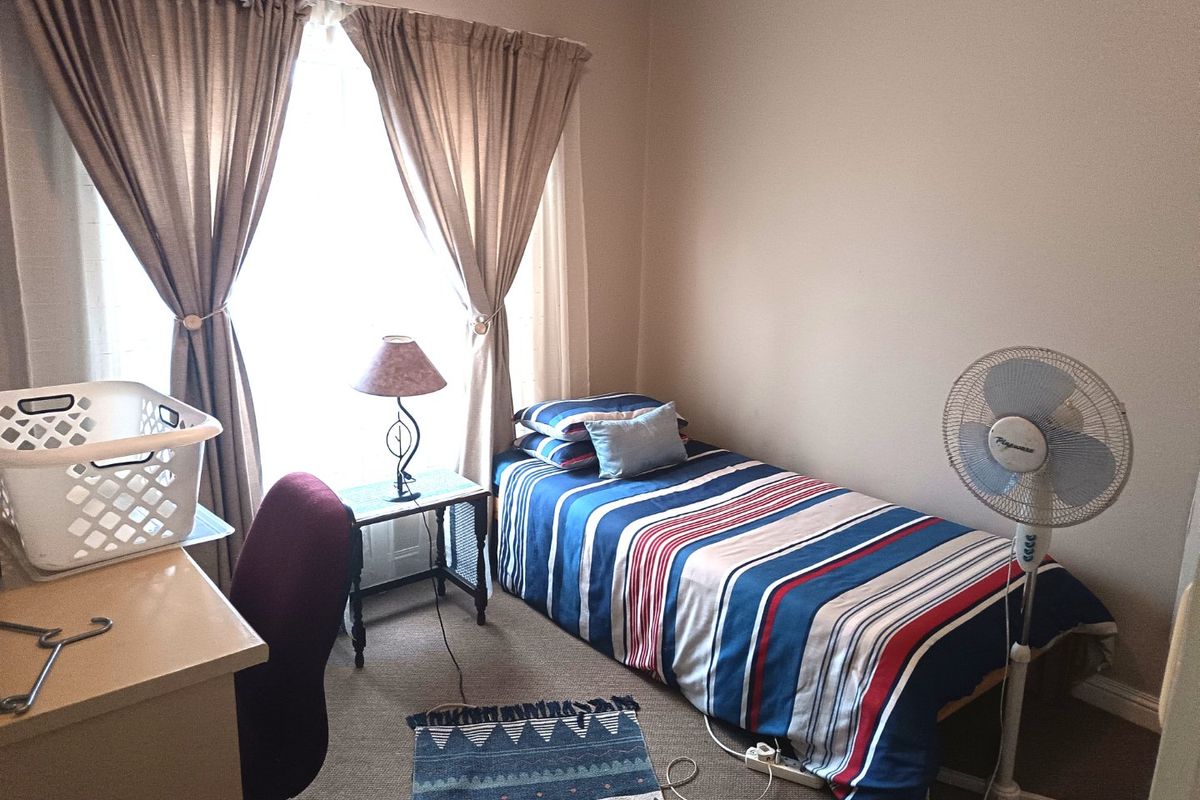 A functional bedroom featuring carpeted flooring and window treatments, providing a comfortable space for rest.