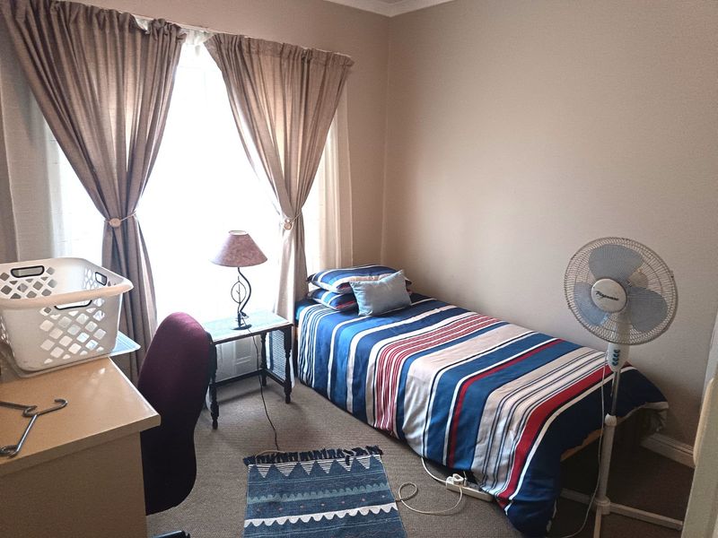 A functional bedroom featuring carpeted flooring and window treatments, providing a comfortable space for rest.