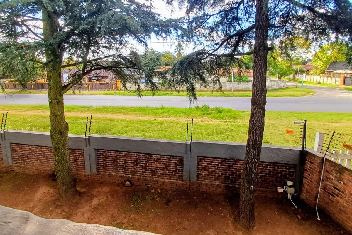 A view of the rear garden area featuring a brick boundary wall with integrated electric fencing and security surveillance.