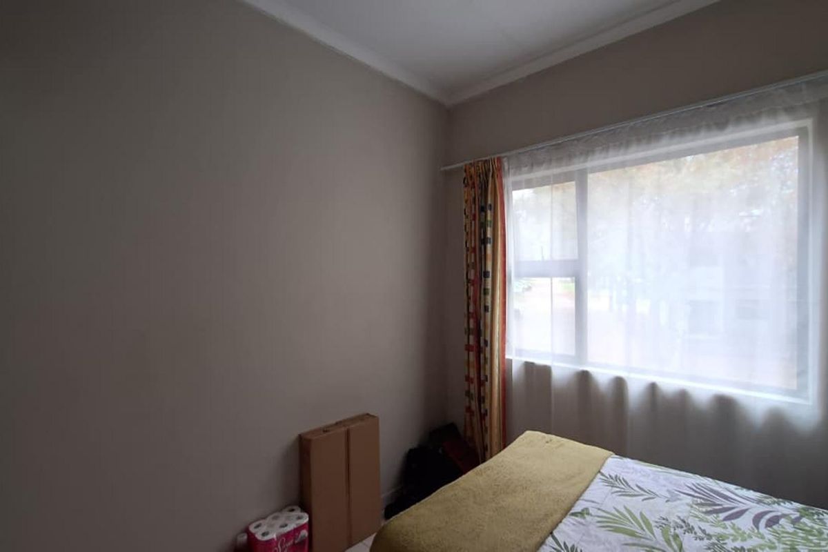 A bedroom featuring a built-in wardrobe and a large window that allows for natural light.
