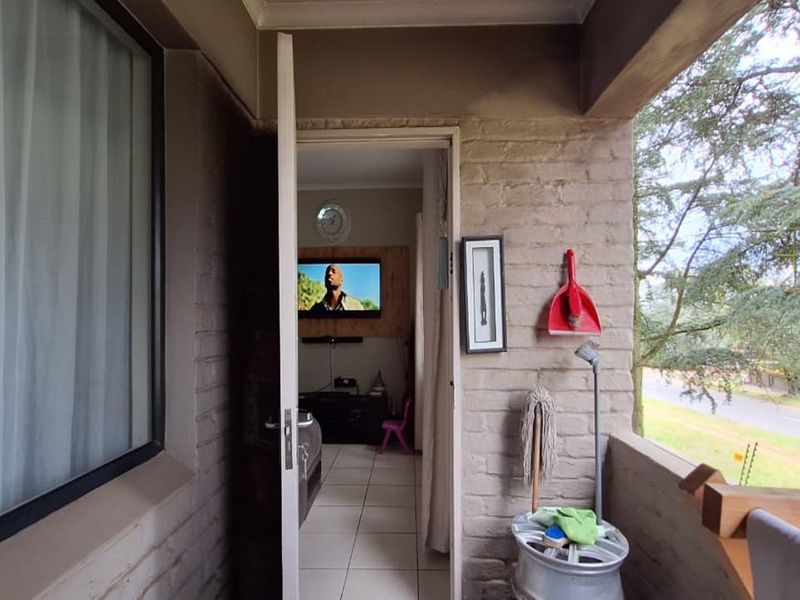 A covered balcony area with brick walls and tiled flooring, providing an outdoor transition space leading into the interior living area.
