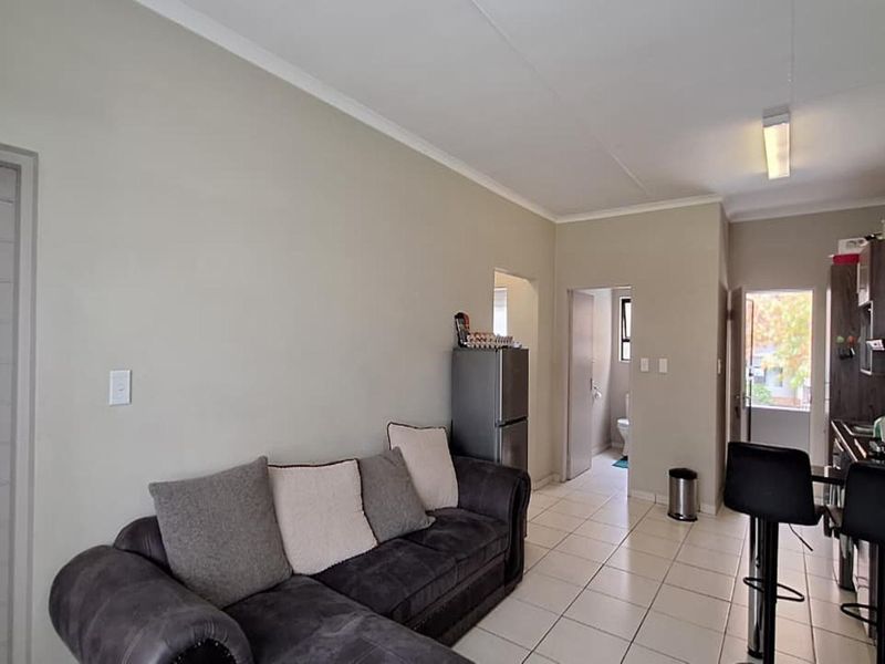 Open-plan living area featuring tiled flooring and a compact kitchen with built-in cabinetry, providing a functional layout for modern townhouse living.