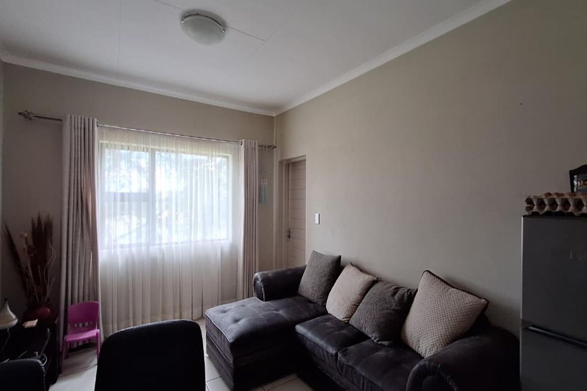 A functional living room featuring neutral wall tones, a large window with curtain fixtures, and standard ceiling finishes.