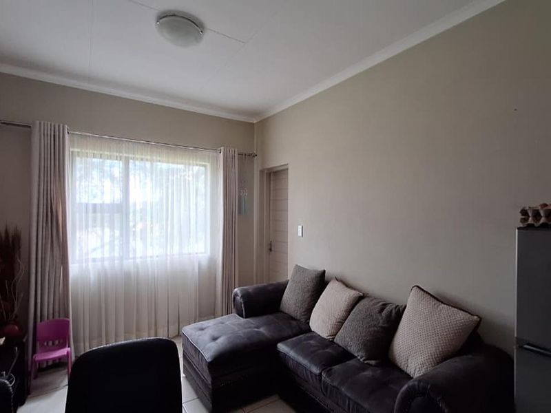 A functional living room featuring neutral wall tones, a large window with curtain fixtures, and standard ceiling finishes.