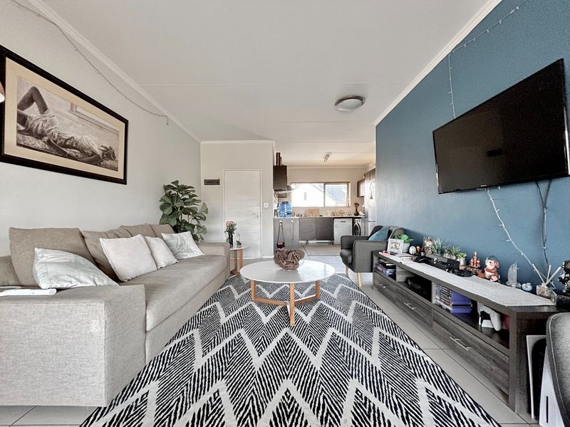 Open plan living area featuring tiled flooring and a seamless flow into the kitchen space, creating a functional and connected home layout.