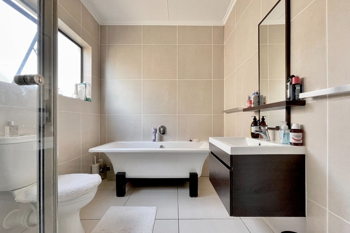 Modern bathroom featuring a freestanding bathtub, wall-mounted vanity, neutral wall and floor tiling, and a separate shower enclosure.