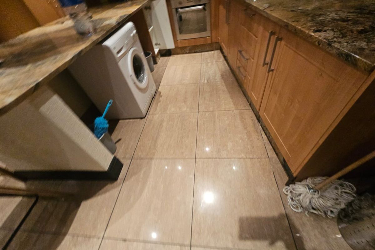 A functional kitchen featuring wooden cabinetry, granite countertops, and tiled flooring, providing a practical workspace with integrated oven and sink.