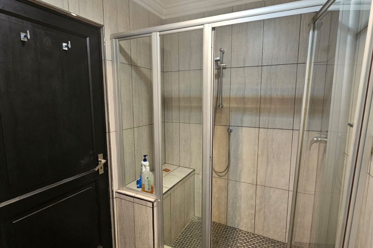 A modern bathroom featuring a walk-in shower with a built-in bench, glass enclosure, and neutral wall tiling.