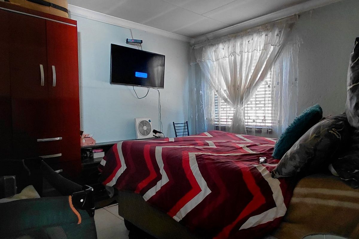 A functional bedroom featuring tiled flooring, a built-in wardrobe, and a window with natural light.