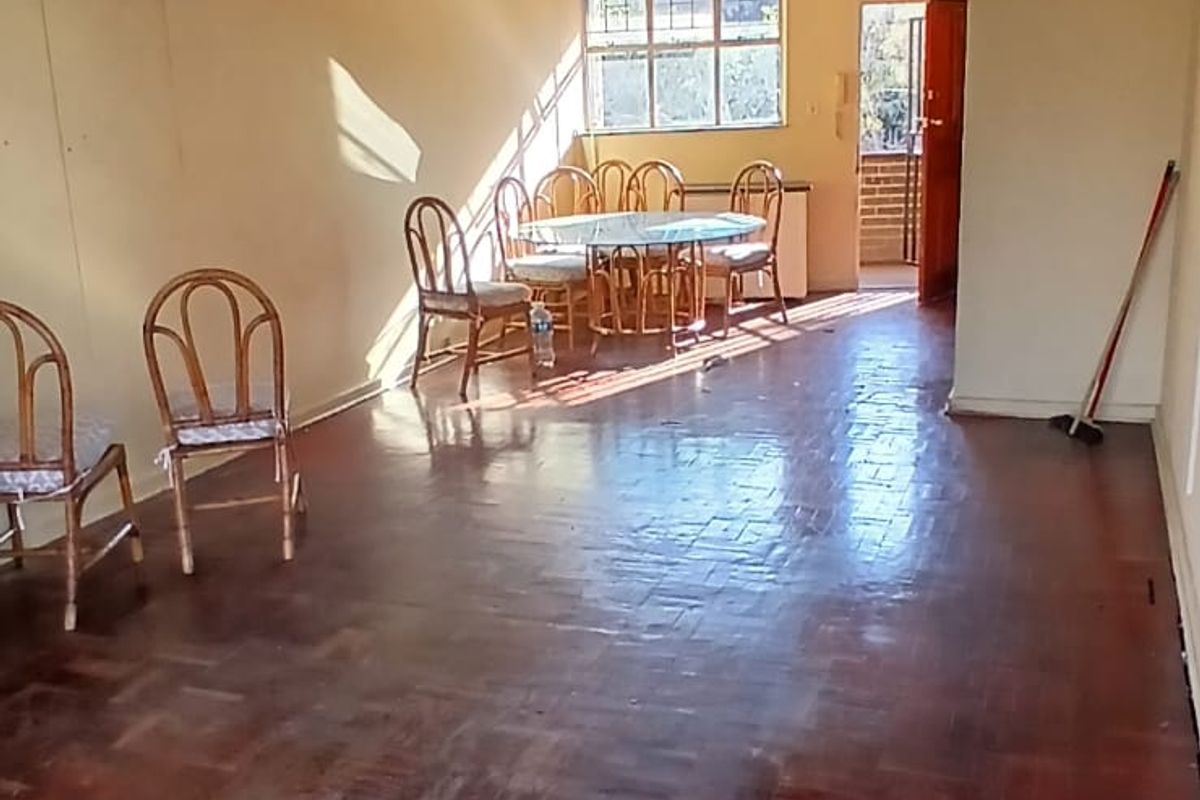 Spacious living area featuring traditional parquet flooring and natural light, offering a blank canvas for modern interior updates.