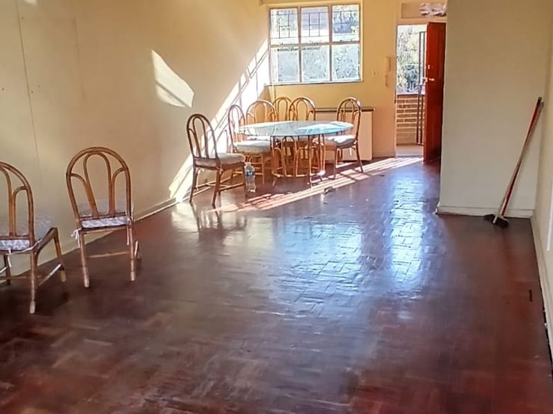 Spacious living area featuring traditional parquet flooring and natural light, offering a blank canvas for modern interior updates.