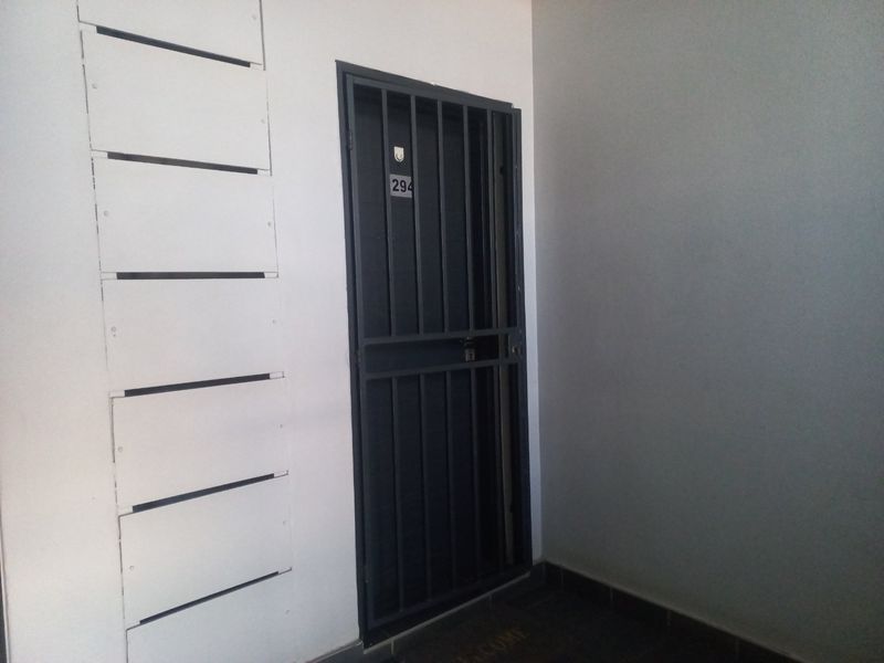 Apartment entrance featuring a secure metal security gate and a bank of wall-mounted letterboxes.