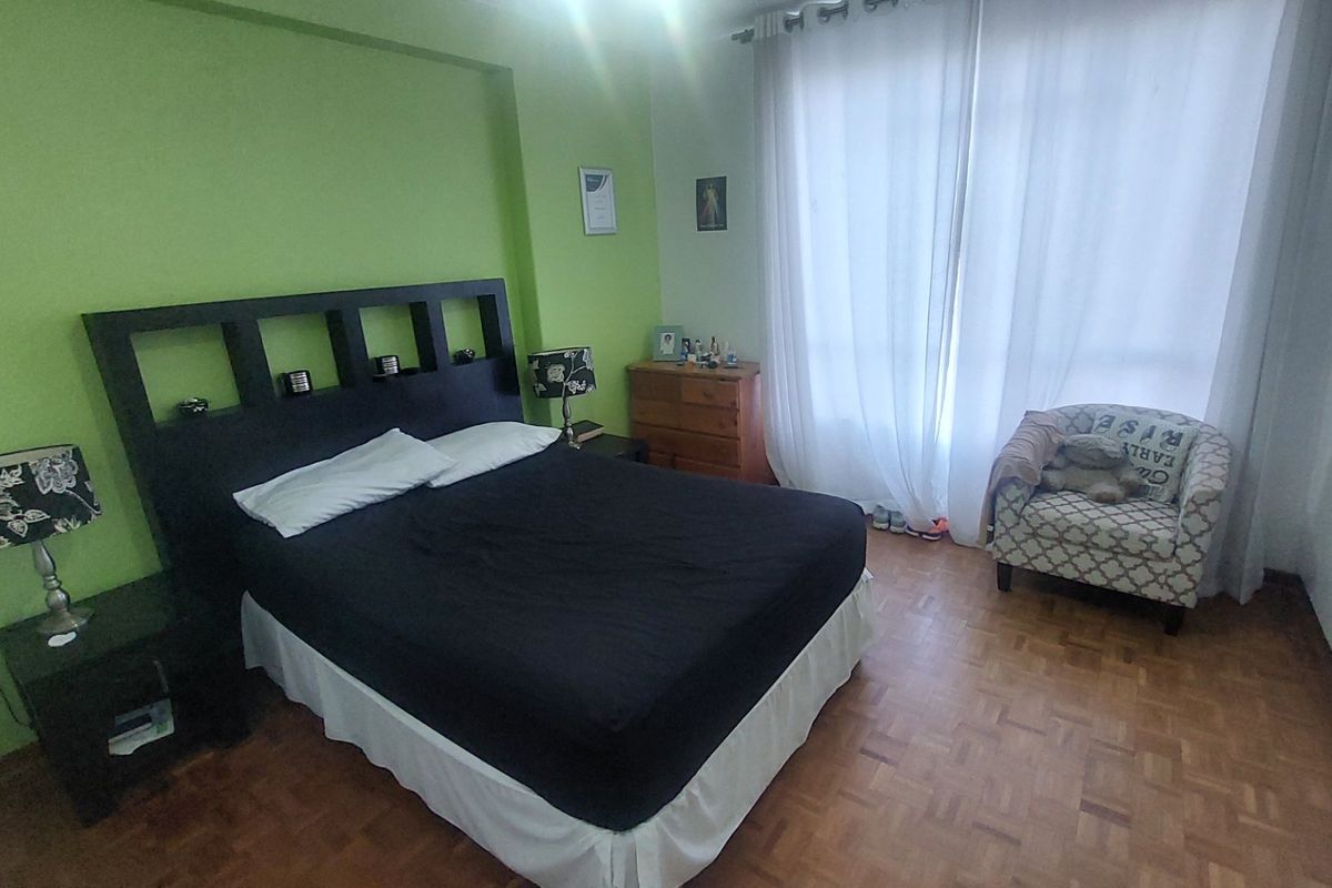A bedroom featuring parquet flooring and a built-in wardrobe, with large windows allowing for natural light.