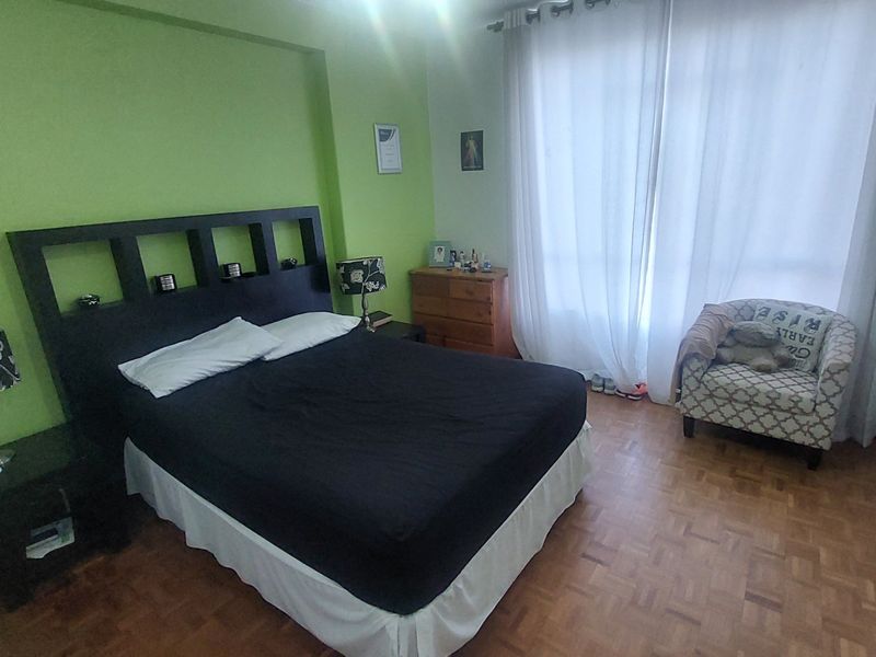 A bedroom featuring parquet flooring and a built-in wardrobe, with large windows allowing for natural light.