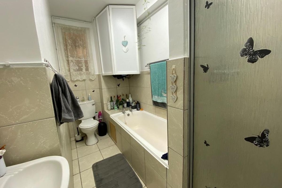 A functional bathroom featuring a bathtub, shower enclosure, toilet, and tiled finishes, offering a practical layout with potential for modern updates.