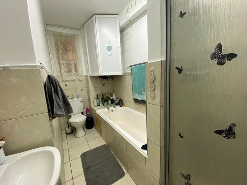 A functional bathroom featuring a bathtub, shower enclosure, toilet, and tiled finishes, offering a practical layout with potential for modern updates.
