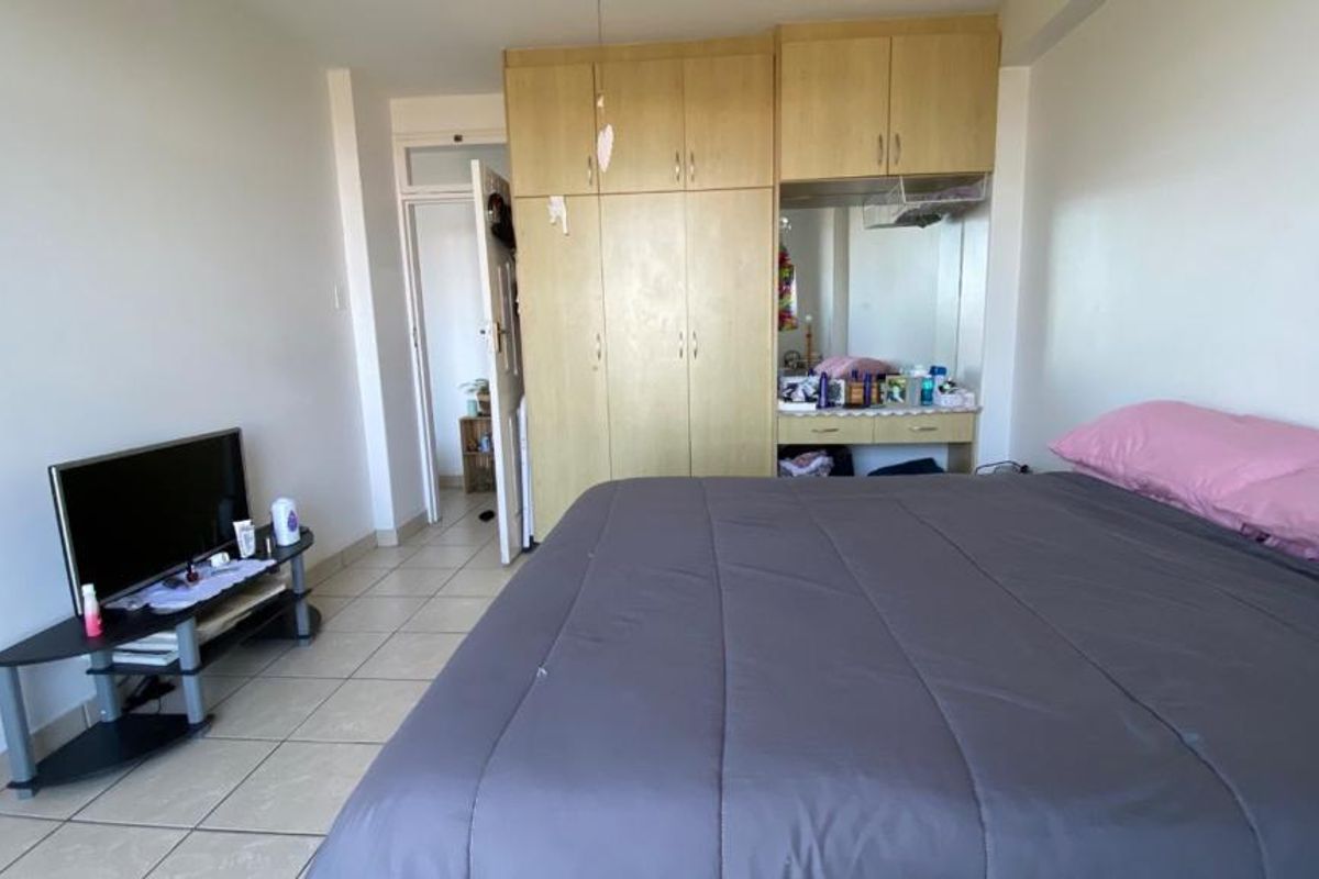 A bedroom featuring tiled flooring and a large built-in wardrobe with an integrated vanity area.