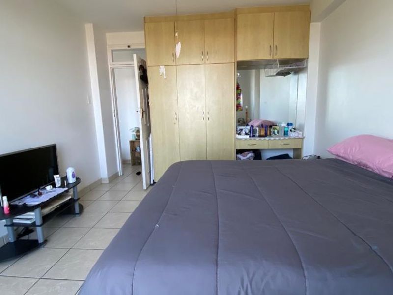A bedroom featuring tiled flooring and a large built-in wardrobe with an integrated vanity area.