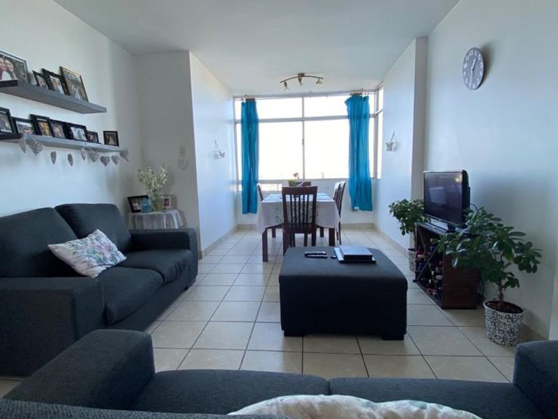 An open-plan living and dining area featuring tiled flooring and a large window that provides natural light to the space.