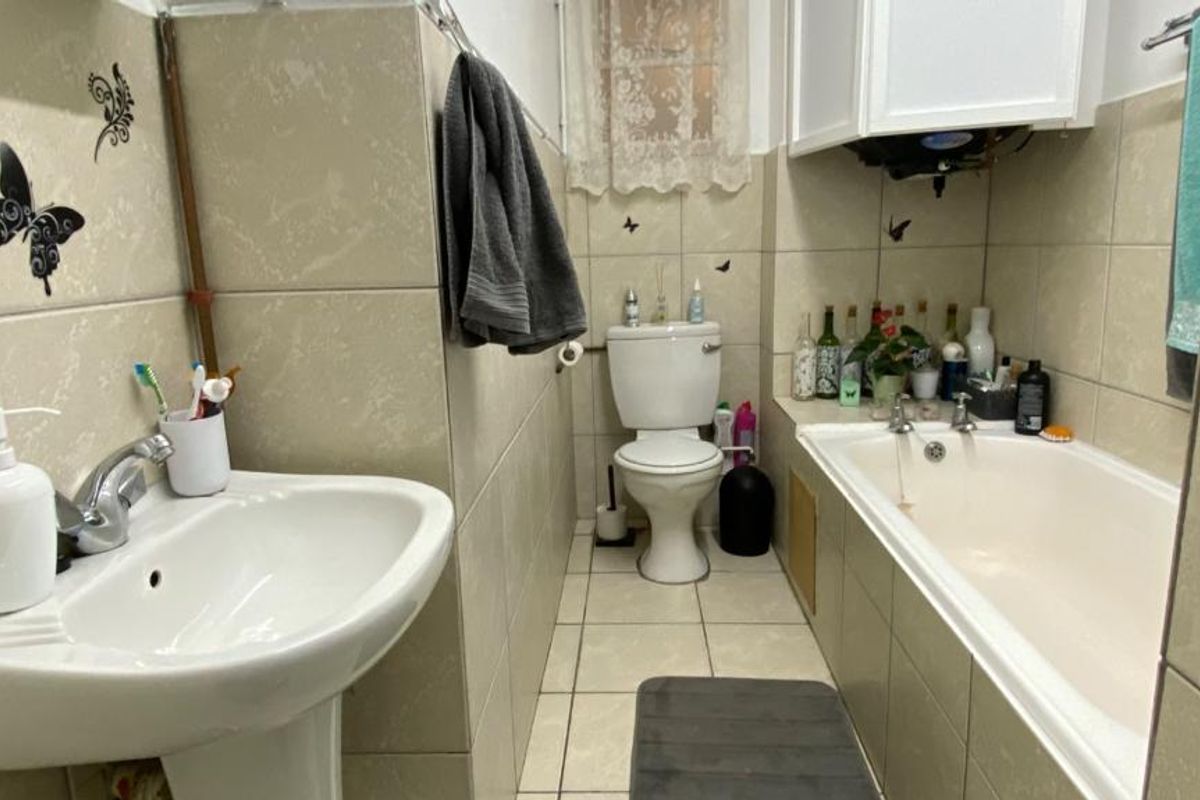 A functional bathroom featuring a pedestal washbasin, standard toilet, and a bathtub with full-height wall tiling.