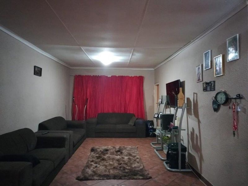 A standard living room featuring tiled flooring and ceiling cornicing, providing a functional space for relaxation.