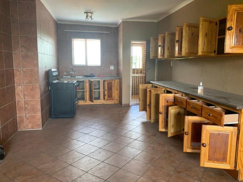 A dated kitchen featuring wooden cabinetry, stone countertops, and tiled flooring, requiring cosmetic updates to modernize the space.