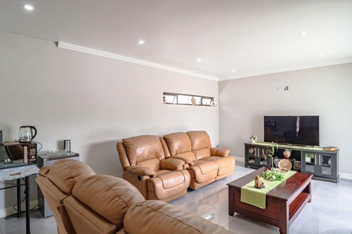 A well-maintained living room featuring neutral walls, tiled flooring, recessed downlighting, and a horizontal clerestory window.