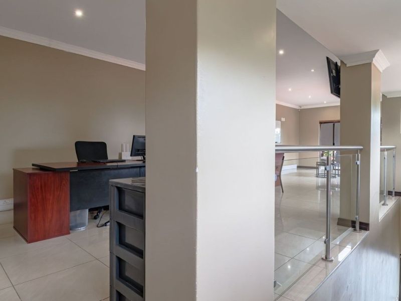 A bright office space featuring tiled flooring, recessed lighting, and a modern glass balustrade overlooking the lower level.