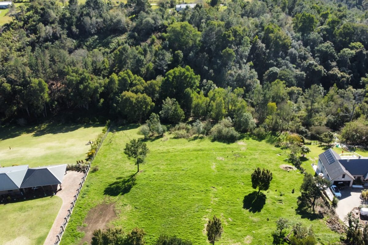 Aerial view of a large, well-maintained residential vacant land plot featuring established trees and fenced boundaries, situated in a scenic, green environment.