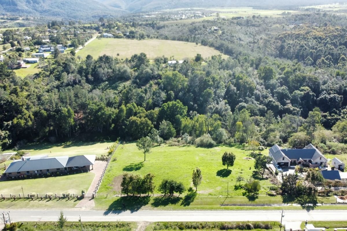Aerial view of a residential vacant land plot situated between existing properties, featuring established greenery and road access.