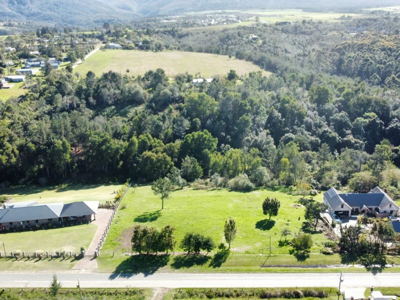 Aerial view of a residential vacant land plot situated between existing properties, featuring established greenery and road access.