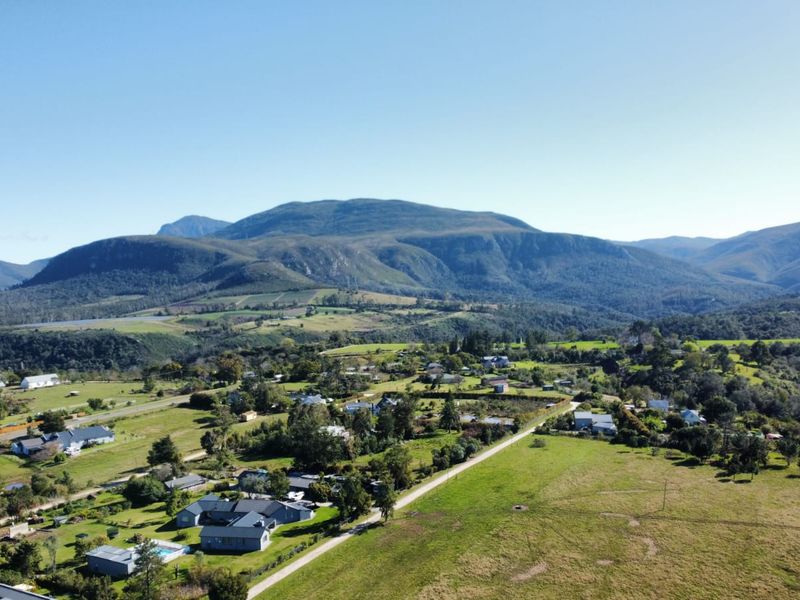 An expansive aerial view of the residential area, showcasing the surrounding landscape, rolling hills, and mountain backdrop.