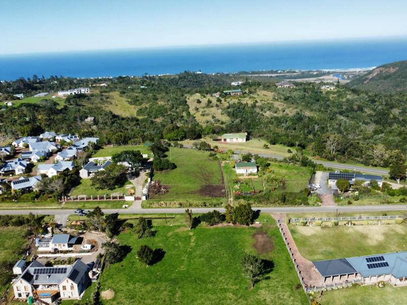 An aerial view of a residential vacant land plot situated within a developed coastal neighborhood, offering scenic landscape views and established road access.