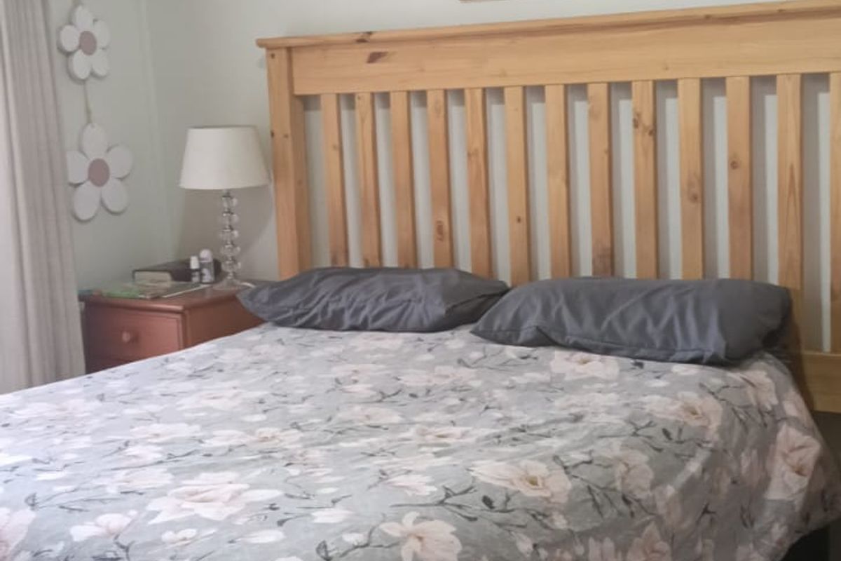 A bedroom featuring a ceiling fan and a wall-mounted split-system air conditioning unit.