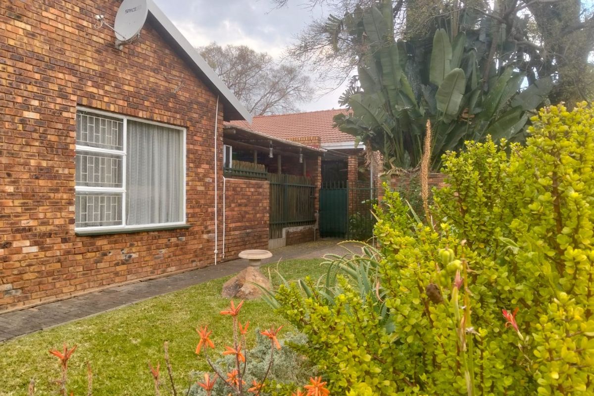 A view of the rear exterior of the townhouse, featuring a face brick facade, a small garden area, and a covered patio space.