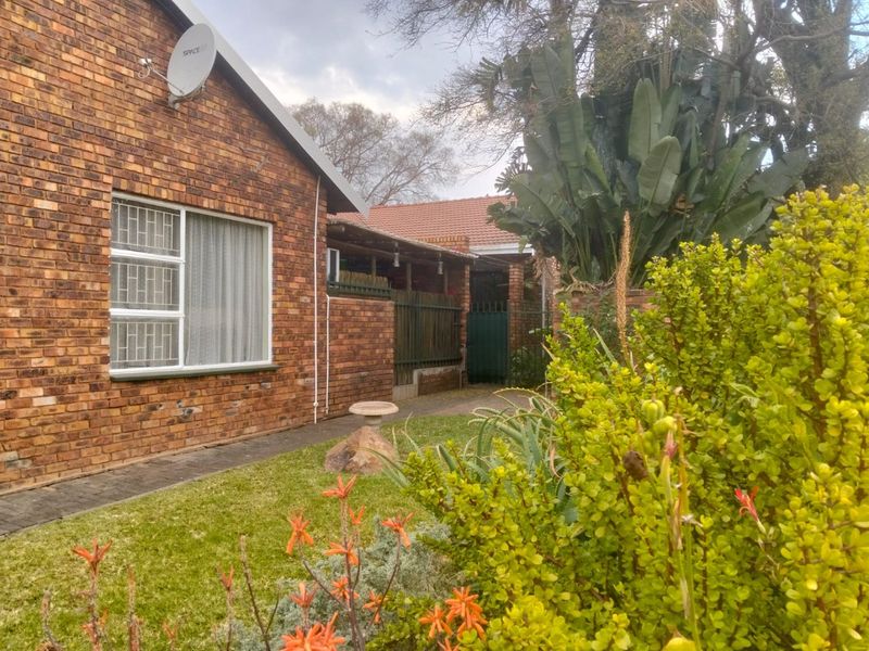 A view of the rear exterior of the townhouse, featuring a face brick facade, a small garden area, and a covered patio space.